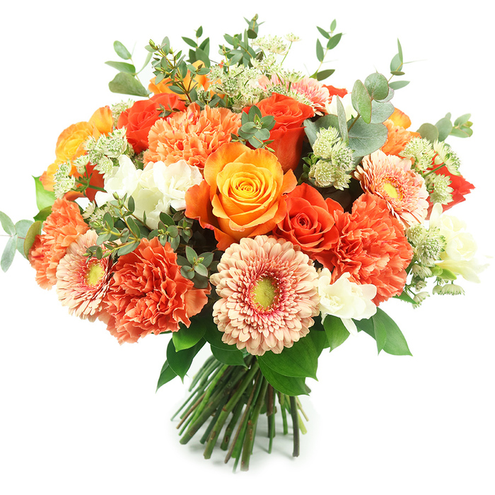 Presented upright against a clean white field, this luxurious hand-tied bouquet blends rich autumnal warmth with delicate, garden-fresh detail. Broad, fully opened roses in golden yellow and deep orange form the visual anchor, each petal layered in a tight, velvety spiral that catches soft light and emits a gentle, floral sweetness. Interspersed are plentiful coral and burnt-orange carnations whose scalloped, multi-layered petals build volume and a tactile softness that contrasts beautifully with the smooth rose faces. Peach-toned gerbera daisies, with their flat, sunburst heads and subtle green centres, lift the arrangement and add a cheerful graphic note. Small, pure-white filler blooms-resembling freesia or tiny spray chrysanthemums-are scattered through the massing of colour, providing luminous highlights and lightening the overall mood. Sprays of pale green flowers that recall astrantia give the bouquet a feathery, almost star-like texture, while generous stems of silvery eucalyptus weave through the design, their rounded leaves offering a cool, muted counterpoint and a crisp, herbal scent. The stems are neatly gathered and tied, the hand-tied shape expertly rounded and dense, making the bouquet feel substantial yet airy. This composition radiates warmth and celebration and would sit beautifully as a centrepiece for an anniversary dinner near Radcliffe Square or as a heartfelt gift delivered to a friend in Summertown. The craftsmanship and fresh, seasonal tones suggest thoughtful floral design rooted in Oxford preferences for elegant, natural bouquets.