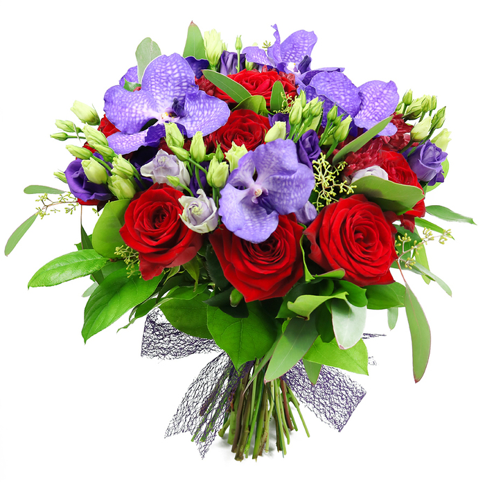 An opulent, hand-tied bouquet dominates the frame against a crisp white background, a testament to careful floral design practiced in Oxford. The arrangement blends deep red roses with striking purple Vanda orchids, their velvety petals and broad forms creating a bold core, while clusters of lisianthus add lilac and indigo softness. Around and among them, lush green foliage-glossy leaves, rounded anchors, and slender sprigs-gives depth, movement, and a natural frame. Unopened green buds mingle with open blooms, signaling ongoing growth and fresh possibility. The stems are neatly gathered at the base and wrapped in a dark mesh ribbon, almost black or deep plum in tone, forming a contemporary, architectural bow that completes the look. The bouquet radiates romance and refinement, a design suited to anniversaries, Valentine's gestures, or a luxurious thank-you gift. In Oxford, it would light a mantel in a Jericho townhouse, brighten a Summertown dining area, or serve as a dynamic centerpiece for a celebratory meal. Flowers Oxford offers reliable, city-wide delivery to ensure freshness and timely arrival. The palette-crimson velvet and royal purples-speaks of passion tempered by sophistication, while the textures-from the soft lisianthus to the glossy foliage-invite touch in addition to sight, making this composition ideal for intimate dinners, grand celebrations, or as a statement gift that elevates any space.