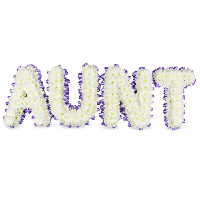 A bespoke sympathy tribute carefully spells out the word A U N T in four substantial, upright letters placed against a pristine white backdrop. Each letter is densely packed with small white spray chrysanthemums, the tightly clustered petals forming a uniform, velvety field that reads both soft and substantial; the tiny pale yellow centres of some florets add a subtle, sunlit detail that prevents the composition from feeling flat. A rich purple satin ribbon outlines every letter, its ruffled, scalloped placement accentuating the letters' contours and producing a graceful frame that contrasts with the luminous white flowers. Soft grey shadows beneath and between the letters lend a three-dimensional quality, revealing the craftsmanship of the underlying frames and the careful spacing that gives each character a presence of its own. In describing this to a family, I would note the gentle, green-tinged fragrance of fresh chrysanthemums that brings a quiet, cleansing aroma to the space without intruding on memories. The colour palette - pure white and dignified purple - is chosen to convey reverence, comfort and a measured celebration of life. Made to be displayed at funeral services, memorial gatherings or beside a headstone, this arrangement reflects the attention to detail and floral technique characteristic of local artisans who work for communities across Botley, the High Street and the university chapels. It is a composed, heartfelt expression of remembrance intended to honour a much-loved aunt with care and respect.