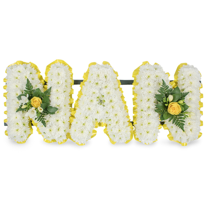 A lovingly assembled sympathy tribute spells out the word 'MAM' in three standalone capital letters, crafted for memorial services, funerals or graveside remembrances. Each letter is densely surfaced with small, pristine white chrysanthemums so that the face of every character appears soft, tactile and luminous, almost cloudlike in texture. Framing each letter is a bright yellow satin ribbon, pleated along the perimeter to create a tidy, uplifting edge that lifts the overall palette from pure white to a warmer, sunlit harmony. Two floral embellishments accent the composition: one is nestled on the left upright stroke of the first 'M' and a mirrored cluster graces the right upright of the final 'M'. Each cluster centres on a softly furled yellow rosebud, encircled by tiny white freesia or similar delicate white blossoms, with layers of deep green foliage and delicate fern fronds that provide contrast and movement. Behind the upper sections a slim dark green or black bar connects and supports the letters, suggesting the arrangement is designed to stand with stability at a funeral service or laid at a graveside by family. The image is photographed against a plain white background so the white chrysanthemums, cheerful yellow accents and glossy greens are immediately clear. In the spirit of local craftsmanship often seen near Christ Church Meadow or the Botanic Garden, this piece balances dignity with gentle brightness-perfect for remembering a mother or maternal figure with warmth, purity and quiet grace.