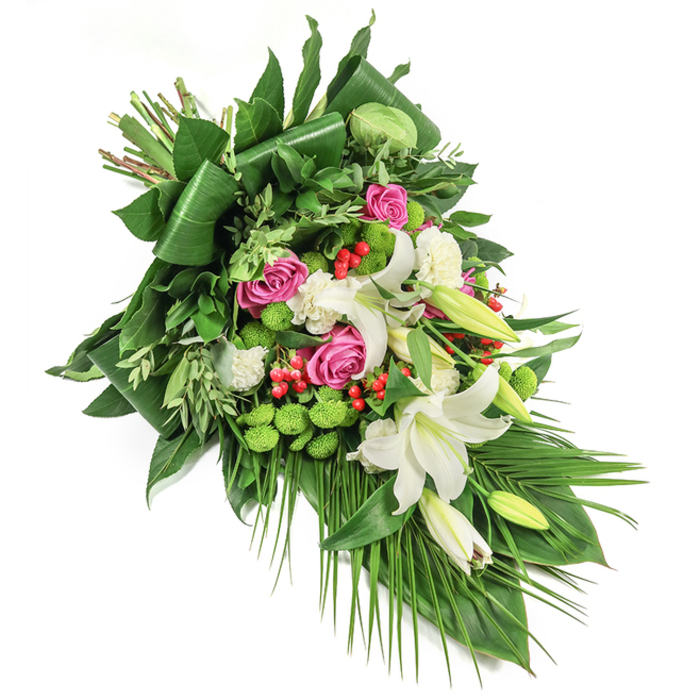 This elegant, elongated sympathy spray is a visual tribute to Oxford's blend of tradition and tranquillity, presented diagonally upon a pristine white canvas. Fragrant white oriental lilies dominate the composition, some openly displaying golden-yellow stamens, others poised in tight, promising buds-each representing purity and remembrance. Interspersed throughout are clusters of vibrant deep pink roses, their gently curled petals adding poignant warmth, mirroring cherished memories along the avenues near Port Meadow. Spherical, lime-green button chrysanthemums introduce modern colour and a unique, tactile texture, their vibrant green resembling the mossy banks by the Cherwell. Miniature, ruffled white carnations fill out the arrangement, bringing softness and continuity. Accents of bright red hypericum berries provide vivid, eye-catching detail, reminiscent of Oxford's rich autumnal hues. Supporting this floral medley, a varied array of fresh green foliage-dark, glossy leaves carefully folded for structure, lighter eucalyptus-like sprays, and stately palm fronds cascading downward-creates lush depth and dynamic movement. The overall effect is a sophisticated and heartfelt arrangement, ideal for expressing condolences, marking a memorial, or honouring a loved one at funeral services across the Oxford area. Each element reflects the meticulous artistry and empathy of Oxford's expert florists, offering solace and reverence through floral beauty.