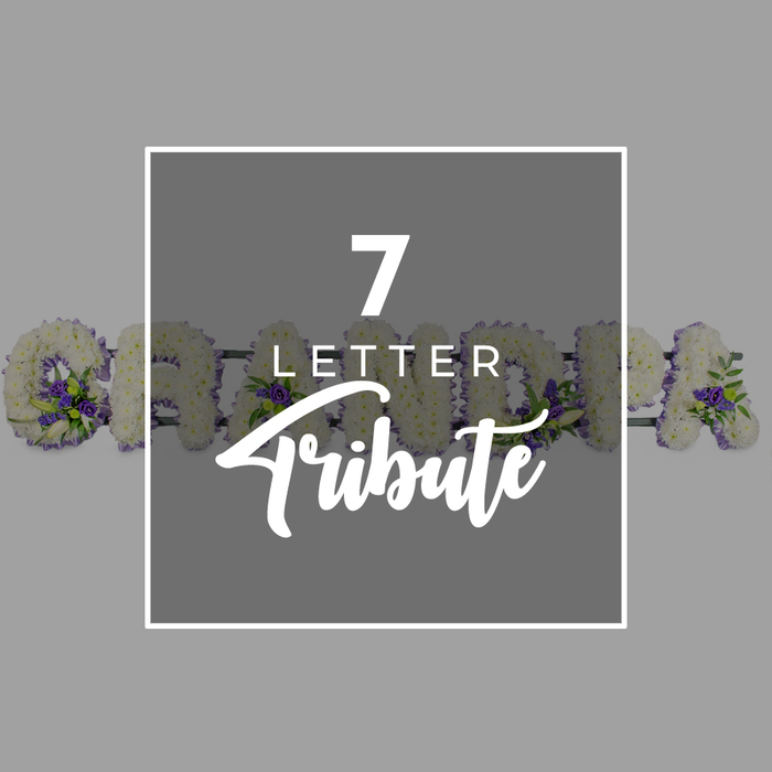 This image captures a tender seven-letter funeral tribute, the kind often chosen by Oxford families to remember a much-loved grandmother. The background is a smooth, light grey, calm and unobtrusive, allowing the floral detail to stand out. In the centre sits a dark grey square bordered with a slim white line, giving the impression of a carefully framed card or memorial plaque. Inside this square, the words 7 LETTER Tribute appear in white: the numeral 7 is bold and commanding at the top, LETTER is set beneath in a smaller, simple font, and Tribute is written in a flowing script that softens the overall look. Around the edges of this central panel, you see most of a full floral name display reading GRANDMA, as if the overlay has been placed gently on top of the tribute. Each letter is formed entirely from compact white flowers, most likely chrysanthemums, tightly massed together to create a full, luxurious shape, with a slight cushion effect that evokes comfort and peace. Scattered among the white are accents of rich purple blooms and glossy green foliage, woven in at the corners and along the curves of each letter to provide depth and a touch of gentle colour. The rounded G on the left is most visible, followed by glimpses of the R, A, N, D, M, and final A as they progress out of frame. The overall feeling is of a bespoke, respectful tribute that might be delivered by a local Oxford florist to a church in Jericho, a chapel in Botley, or a quiet crematorium on the edge of the city, carrying the family's love in flowers when words fall short.