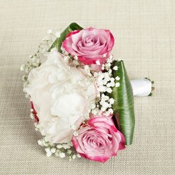 With the golden afternoon light of Oxford's historic colleges filtering through, this delicately composed bouquet rests upon a tactile ivory linen, capturing the city's blend of tradition and elegance. Bold, full-bloomed pink roses anchor the design, their petals gracefully shifting from striking fuchsia to a wistful blush and soft lavender at their tightly coiled hearts. At centre, a magnificent white peony unfurls layer after layer of plush, ruffled petals, suggesting both gentle opulence and spring's renewal along the banks of the Cherwell. Sprigs of baby's breath wend their way between the larger blooms, their tiny, airy flowers sprinkling a dreamy, romantic texture evocative of meadows on the edge of town. The bouquet is handsomely framed with broad, lustrous green leaves, their deep emerald sheen and crisp curves reminiscent of foliage found in University Parks. Binding the stems together, a smooth white satin ribbon offers a touch of refinement and the sturdy functionality required of a bridal or bridesmaid bouquet. Every petal, sprig, and fold is picked out in soft, natural lighting, highlighting a careful composition that balances structure and spontaneity. The overall sensation is one of quiet joy, gentle fragrance, and meaningful celebration-perfect for a wedding near Broad Street or for delivery to a loved one living under Oxford's dreaming spires.