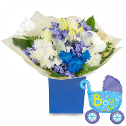 Soft morning light illuminates a joyful newborn gift: a lush round bouquet set in a matte royal-blue presentation box beside a jaunty baby-pram foil balloon proclaiming It's a Boy. White roses nestle into the center with a poised, timeless grace, while unopened white lily buds suggest new life and add a faint, sweet perfume that lifts when you draw near. Plump white chrysanthemums provide generous, cloud-like volume, balanced by vivid electric-blue chrysanthemums that serve as a bold, celebratory focal point. Interspersed clusters of pale lavender or periwinkle blooms-hyacinth-like in form-add delicate texture and a cool, calming counterpoint to the brighter blues. A variety of green foliage, from glossy broad leaves to feathery fern fronds, creates depth and a feeling of freshly gathered greenery from a market stall. The stems are swathed in crinkled cream tissue and presented within a sturdy rectangular royal-blue gift box, giving the arrangement a tailored, keepsake quality. Floating at the side, the light blue carriage balloon is detailed with darker blue trim, heart and polka-dot motifs, and yellow-green lettering that reads It's a Boy, which brings a playful finish to the set. Crafted with the same care we use for deliveries across Oxford-from Jericho to Summertown-this composition reads as a warm, reliable welcome for a newborn son and makes an ideal hospital or home-coming present. Available for local delivery, it balances classic white florals with a confident pop of boy-blue for a distinctly celebratory tone.