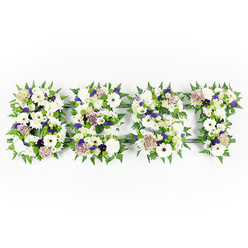 This tapestry-like sympathy arrangement spells out DAD in broad, comforting letters, each one assembled from a soothing palette of whites, soft purples and fresh greens against a clean white background. Prominent, velvety chrysanthemums and ivory gerberas form the backbone of the letters, their broad faces delivering a calm, open presence, while pale, coffee-toned roses - soft pastel roses with a warm taupe blush - bring a gentle, familiar richness to the composition. Ruffled white carnations and delicate lisianthus (eustoma) add softer textures and quiet fullness, and small sprays of violet statice or deeper purple filler flowers weave through the design to lend depth and a tender hint of color. The edges of every letter are lined with lively fern fronds whose crisp, feathered shapes frame the petals and create a sense of movement; compact green button chrysanthemums are scattered within the fields of blooms, punctuating the whites with fresh green highlights. The dark grey or black structural base peeks through in places, defining the letters with subtle contrast and ensuring the word reads clearly from above. I picture this piece being prepared in our workshop with the calm rhythm of a late-afternoon service in Jericho or a quiet chapel near Port Meadow - the scent of cut flowers is faint and consoling - and available for careful delivery across Oxford when families ask for a deeply personal tribute. The overall mood is one of solemn affection: precise, crafted, and offering a tangible expression of remembrance when words alone are not enough.