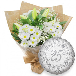 Displayed against a bright, uncluttered white backdrop, this image captures a sophisticated silver anniversary gift: a lush white bouquet paired with a shimmering metallic balloon marking 25 years. The hand-crafted bouquet features an abundance of fresh white chrysanthemums, each blossom framed by tidy petals around a vivid yellow centre that adds a gentle warmth to the otherwise cool palette. Tall, closed white lily buds rise gracefully from the arrangement, their elongated forms and subtle green-tinged tips lending poise and anticipation, as though they are waiting to unfurl for the couple's next chapter together. Wisps of baby's breath thread through the design, thousands of tiny white flowers softening the lines and giving the arrangement the light, cloud-like texture that florists in Oxford often favour for romantic pieces. Rich, dark green leaves curve behind and between the blooms, providing both support and a velvety backdrop that intensifies the brightness of the whites. The flowers are wrapped in a layer of clear cellophane for structure, then embraced by rustic brown kraft paper, folded into clean angles and gathered firmly at the stems, ready for delivery to an Oxford college quad or a townhouse near Summertown. Just to the lower right of the bouquet sits a round silver foil balloon. Its surface gleams, etched with ornate scrolling patterns in deeper grey and silver. At the heart of the balloon, the inscription "25th" flows in elegant script, while the faint phrase "Happy Anniversary" repeats in the background, making this pairing an understated yet heartfelt tribute to a quarter-century of love in the city of dreaming spires.