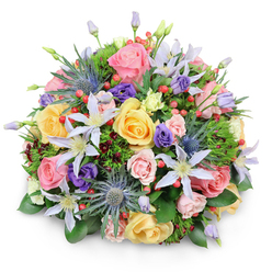 Presented on a clean white surface with a delicate shadow, this compact, domed bouquet blends romantic pastels and jewel tones in a way I often design for neighbours around Jericho and the Botanic Garden. At its heart are plentiful garden roses in soft pink, warm yellow and peachy cream - classic garden-scented blooms whose layered petals create a luscious, tactile centre. Interwoven among them are pale lavender-to-white clematis flowers with star-like petals and pale yellow centres, introducing a light, airy movement. The arrangement's sculptural punctuation comes from several deep-blue Eryngium (sea holly) thistles: spiky, silvery-blue globes that offer dramatic texture and a subtle architectural edge. Scattered throughout are velvety purple lisianthus in varied opening stages, together with groups of bright red Hypericum berries that add small, glossy punctuation marks of colour. Underpinning everything is a lush assortment of foliage - broad glossy leaves anchoring the base, delicate feathery greens adding depth, and hints of burgundy-toned sprigs to give contrast and shadow. The composition and balanced scent evoke a quiet garden on a mild morning, and the soft lighting emphasizes the varied textures from silky petals to bristly thistle heads. Crafted with the same attention to proportion and freshness I bring to local deliveries, this bouquet - a mix of romantic and contemporary elements - suits birthdays, anniversaries, thank-you gestures or a refined centrepiece for a gathering in central Oxford. Flowers Oxford often pairs these botanicals to reflect the city's timeless yet lively character.