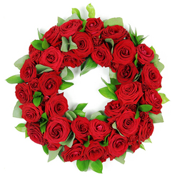 In my hands, this circular wreath of red roses feels ceremonial, as if each petal had been woven with heartfelt care and reflection. The depth of the blooms is tempered by silvery-green foliage, peeking out in gentle crescents like breaths of calm amid intense emotion. The roses, classic symbols of love and enduring devotion, create a mood of reverence, their velvet surfaces catching the soft light and releasing a subtle garden scent that lingers in memory. Light falls over the ring with a quiet sheen, highlighting the petals' intricate folds and giving the arrangement a warm, serene glow. Crafted as a symbol of eternal connection, this piece transcends mere décor, offering solace in its beauty and a promise that memories, like flowers, endure. In Oxford, such a wreath finds its place in ceremonies across Jericho, Summertown, and the university wards, becoming a dignified focal point for condolences, memorials, or anniversaries. Its generous fullness conveys both presence and restraint, a refined tribute that respects tradition while speaking of personal remembrance. Delivered with careful attention to freshness and handling, this wreath travels across the city to be placed with quiet grace at a church, chapel, or family home, a tangible reminder that love remains after loss. The soft fragrance and the velvet touch of the petals can console during long vigils in quiet rooms along the High Street, and the wreath's circle echoes the ongoing cycle of memories cherished by Oxford families in the days after bereavement. For those arranging a small ceremony in Port Meadow or the Oxford Covered Market, its presence is a comforting, timeless gesture.