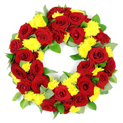A meticulously crafted circular funeral wreath appears against a crisp white backdrop, its ring of flowers so dense and even that it seems to float in space. At its heart are generous clusters of deep red roses, each bloom fully open yet still neat, with velvety petals curling gently at the edges and forming classic spirals that draw the eye inward. Between these rich crimson and burgundy tones, sunny yellow chrysanthemums are tucked in, their rounded, almost feathery heads adding a soft, cushion-like texture and a burst of brightness that softens the solemnity of the red. The flowers rest on a bed of layered greenery: smooth, glossy dark green leaves provide structure and fullness, while cooler, slightly muted leaves with a silvery cast hint at eucalyptus, suggesting a subtle, calming fragrance. The foliage peeks through just enough to frame the blossoms without breaking the wreath's continuous circle, which symbolises eternity and enduring memory. The lighting is bright and even, casting no harsh shadows, so the red roses, yellow blooms, and fresh greens appear as vivid as if they had just been arranged in a florist's studio off Oxford High Street or near Headington. There is a quiet balance between formality and warmth, making this wreath feel appropriate for a church service in central Oxford, a crematorium chapel near Cowley, or a family gathering to remember a loved one at home. The overall impression is of a respectful, heartfelt floral tribute, carefully designed to offer comfort, express deep love, and honour a life with grace.