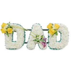 An elegant funeral tribute crafted in three-dimensional letters spelling DAD, each letter formed from a dense, snow-white mass of spray chrysanthemums that feel soft to the eye and comforting to the touch. The letters are trimmed with a ruffled dark green satin ribbon that gives definition and a refined contrast to the white surface, while discreet dark green metal bars behind the composition connect and support the pieces as a single, dignified display. Bright yellow roses cluster on the upper curves of both outer Ds-cheerful, sunlit blooms grouped with small white freesia or gypsophila and fresh green leaves-evoking memories of warm afternoons and laughter. Two graceful bare green stems extend from the left cluster toward the centre, their sweep guiding the eye to the A, where two deep purple to burgundy calla lilies form a solemn, sculptural heart on the lower diagonal, surrounded by delicate white fillers. The arrangement sits against a plain white backdrop under gentle lighting that brings out the ribbon's sheen, the chrysanthemums' soft ripples, and the callas' satin-like surface; there is a subtle, clean floral scent threaded through the composition. Crafted with careful proportion and emotional thought, this DAD tribute is meant to comfort grieving families and is the sort of bespoke piece our studio would prepare for services across Oxford, from the Botanic Garden funerals to small chapels near Carfax, offering a quiet statement of love, remembrance, and respect.