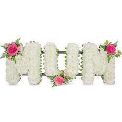 A carefully composed floral tribute spelling "MUM" is displayed against a clean white studio background, the simplicity of the setting allowing every petal and curve to stand out. The three capital letters, shaped in classic block style, are densely paved with small white spray chrysanthemums, each bloom pressed closely to the next so that no gaps interrupt the snowy surface. Their rounded, velvety heads form a thick, cushion-like texture that suggests comfort and purity, much like the calm that can settle over Oxford's Botanic Garden early in the morning. Beneath the blossoms, a dark green frame and ribbon can be glimpsed at the base of each letter, anchoring the arrangement and adding a subtle band of colour. To soften the crisp white, the florist has placed luxurious accent clusters at three key points: at the top left of the first "M", at the gentle dip in the lower centre of the "U", and at the top right of the final "M". Each cluster contains a bold fuchsia rose surrounded by paler pink spray roses and tight rosebuds, woven through with feathery green fern leaves that trail lightly over the chrysanthemums. The interplay of bright pinks, fresh greens, and calming whites creates a tender composition, evoking memories of a much-loved mother. This is the kind of personalised funeral tribute families around Oxford might request for a service in Headington or Summertown, a floral message of devotion and farewell designed to rest near the coffin or be placed later at a graveside.