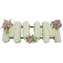 A lovingly designed floral tribute from Flowers Oxford spells MUM in bold, capital letters, each letter densely covered with thousands of small, crisp white chrysanthemums that create a plush, pillowy texture across the surface. The pristine white conveys purity and peace; under a gentle morning light the blooms appear almost luminous, their tiny petals layered like soft coin stacks. Three carefully placed clusters of accent roses - muted lavender tones intermingled with delicate pastel pink buds - break the expanse of white with quiet elegance: one adorns the upper left arm of the first M, another nestles in the gentle curve of the U, and the third highlights the upper right arm of the final M. Interwoven fern fronds and bright green leaves give the tribute depth and a natural rhythm, the darker foliage underscoring the pale palette and guiding the eye across the letters. A discreet dark green support, possibly ribbon-wrapped or moss-lined, is visible at the base, providing structural unity and a subtle framing that keeps the arrangement architectural yet soft. Thoughtfully composed for a funeral or memorial service in Oxford and its neighbourhoods-whether delivered to a family home in Jericho, a chapel near Port Meadow, or a service at Headington-the piece carries a message of deep respect and remembrance. As a local florist describing the work, I notice the soothing scent of the roses against the clean chrysanthemum air and the way the pastoral colour balance offers comfort, making this a timeless tribute for a beloved mother.
