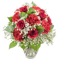 A rich, romantic bouquet of red and white blooms stands proudly in a clear glass vase, set against a clean white background that highlights every detail of the design. At the centre, deep red roses with tightly layered, velvety petals form elegant spirals, each flower poised between bud and full bloom, suggesting affection just on the verge of spilling over. Surrounding them, abundant red carnations create a soft cushion of colour, their finely frilled petals adding volume and a sense of movement, like ripples of crimson fabric. A mist of white baby's breath threads throughout the bouquet, thousands of tiny blossoms forming a cloud-like halo that softens the intensity of the reds and brings a sense of innocence and serenity. Interwoven greenery, from glossy dark rose leaves to rounded eucalyptus with its subtle silvery-green tone, introduces texture and a gentle, herbal freshness. The stems, clearly visible through the transparent vase and clear water, show careful conditioning and thoughtful, professional preparation. The lighting is bright and even, much like daylight spilling through a window of a townhouse near Oxford's Cowley Road or a café off Broad Street, giving the arrangement a fresh, modern feel while maintaining its traditional charm. This bouquet speaks of love, gratitude, and quiet celebration, suitable for an intimate anniversary dinner in Headington, a romantic surprise in East Oxford, or a meaningful thank you delivered across the city by a local florist who understands Oxford's blend of history and heartfelt moments.