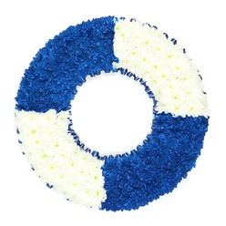 A carefully composed floral wreath in the form of a lifebuoy is shown against a spotless white backdrop, its bold blue-and-white pattern immediately evoking maritime imagery and the sense of protection and care associated with a life ring. The circular tribute is densely carpeted with tiny chrysanthemum-style blooms, each head nestled closely beside the next so that the texture appears smooth and cushioned, yet alive with hundreds of individual petals. The ring is evenly divided into four segments: two opposite quadrants in rich, dark royal blue and two in pristine white, creating a rhythmic alternation of colour that feels both graphic and soothing. The blue sections are intense and velvety, while the white areas bring light and clarity, much like the contrast between shadowed water and bright sky along Oxford's riverbanks and canals near Jericho and Port Meadow. A slim band of dark blue ribbon, folded into subtle pleats, runs neatly around the inner edge of the circle, adding a fine, tailored finish and echoing the straps of a real lifebuoy. The open centre of the wreath is clearly visible, reinforcing the iconic life ring silhouette and drawing the eye inward to a calm, empty space that suggests reflection, remembrance, and safe harbour. Created as a funeral or memorial tribute, this floral lifebuoy would feel particularly poignant for services in Oxford honouring someone with a connection to sailing, rowing on the Cherwell, maritime service, or a life spent guiding and supporting others, offering a quietly powerful symbol of rescue, gratitude, and enduring love.