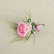 On a calm, light beige backdrop with a woven, linen-like texture, a beautifully crafted pink rose boutonniere lies as if just set down by a careful florist in an Oxford workshop. The rose sits slightly diagonally, its bloom full yet youthful, with outer petals tinted in deep fuchsia gently melting into soft, pastel pink at the centre. The petals curl inwards in concentric layers, creating a sense of movement and quiet anticipation. Clusters of delicate white Baby's Breath nestle around the rose, their tiny star-shaped florets bringing a sense of lightness, like little puffs of cloud over Port Meadow on a spring morning. Fine, grass-like fronds of greenery stretch beyond the blossom, adding height and a natural, slightly untamed feel that contrasts beautifully with the rose's polished elegance. At the base, a single broad, emerald green leaf wraps partway around the stems, its surface catching a few clear droplets that suggest cool freshness and recent care. The stems are tightly banded in a satin ribbon, primarily a soft blush or lavender-pink, with a slightly deeper magenta bow tied crisply at the base, a small but thoughtful flourish. The lighting is gentle and even, enhancing the subtle sheen of the ribbon and the velvety texture of the petals without casting harsh shadows. This boutonniere feels ideal for an Oxford wedding at a city church or a registry office near the High Street, a refined accessory that speaks of romance, craftsmanship, and the simple beauty of one perfect rose.