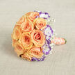 This bouquet reads as a gentle declaration - peach roses unfolding like soft dawn, arranged in a rounded, generous cluster that looks both opulent and comfortably held. Shot from above and set against a neutral, textured beige cloth that resembles natural linen, the composition feels purposely simple so the flowers may sing. The roses, in warm peach and soft orange, show layered petals that fold inward with a velvet softness; between them, white lisianthus with their distinct violet-tipped edges introduce an elegant, slightly edgy contrast, as if twilight met sunrise within the same arrangement. Tiny sprigs of baby's breath drift through the bouquet like confetti, lending a delicate, celebratory air and softening the visual transitions between the larger blooms. The stems are bound in a satin ribbon of pale peach-coral, its sheen catching a whisper of light, while a strand of off-white pearls coils around the handle, bringing a handcrafted, heirloom quality. The bouquet's horizontal placement and subtle shadowing suggest a calm morning in Oxford - perhaps the last quiet moment before a ceremony in the covered arcade of the Oxford Covered Market or on the steps by Radcliffe Camera. Texture is central here: silky petals, ruffled lisianthus edges, feathery gypsophila, and the slightly rough weave of the linen beneath. It invites touch, promises scent, and carries an emotional weight suited to weddings, anniversaries, or vow renewals - an emblem of tenderness, meticulous technique, and thoughtful colour balancing.