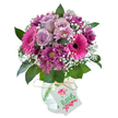 A rich, uplifting floral bouquet stands out against a pure white background, expertly assembled for delivery in Oxford. The full, dome-shaped arrangement spotlights several soft lavender roses, their blooms delicately opening at the center, surrounded by an array of large, hot pink Gerbera daisies and deep magenta chrysanthemums with yellow-green eyes. Sprigs of white baby's breath are interlaced throughout, offering a fresh, airy touch that brings balance and a feeling of lightness to the display. Vibrant green leaves peek through, enhancing the oval silhouette and nodding to the lush greenery of Oxford's River Isis banks. All flowers rest artfully in a unique clear glass vase with a frosty, fractured finish that plays with light-a subtle reminder of Oxford's classic windows and heritage glasswork. The neck of the vase is adorned with simple raffia twine, tied with a white rectangular tag for gifting, making it ideal for celebrating birthdays near the Covered Market or sending a warm thank you to homes in Iffley or Jericho. Fragrant, inviting, and full of character, this bouquet embodies both the skill of local florists and the joyful spirit of Oxford, offering a thoughtful gesture perfect for any special moment shared in this historic city.