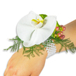 A refined wrist corsage sits gently on a fair-skinned wrist against a clean white background, the composition photographed to emphasise texture and colour. At its centre is a single, large white Phalaenopsis orchid - the moth orchid - its broad, satiny petals unfolding with quiet grace. The orchid's labellum shows a bright yellow throat washed with deeper orange tones, a small, vivid sunburst that draws the eye inward. Beneath and around the bloom, soft, feathery asparagus fern creates a cushion of bright green that both frames and lifts the flower, its fine fronds catching a hint of shadow for dimensionality. To the orchid's upper right, a compact cluster of glossy Hypericum berries moves through a gentle colour shift from pale green to rose and warm cranberry red, giving the arrangement seasonal depth and a slightly rustic note. Near the berries, ruffled lime-green accent foliage adds a crisp textural counterpoint. The floral cluster is secured to the wrist by multiple strands of tiny, lustrous white pearls that wrap comfortably, their cool sheen contrasting with the orchid's smooth velvet and the fern's delicate lace. In soft, natural light - like an Oxford morning beside University Parks or the Covered Market - the corsage reads as timeless and intimate, smelling faintly of fresh cut greenery with the orchid's whisper of sweetness. This is a bridal or prom accessory designed to sit lightly through vows or a first dance: elegant, understated, and handcrafted with the care a local florist would take for a ceremony on High Street or a walk along Christchurch Meadow.