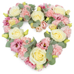 A luxurious, heart-shaped floral wreath stands out sharply against a clean white background, its pastel tones and lush greenery combining into a tender, comforting tribute often chosen for funerals and memorials in Oxford. The heart is perfectly formed and generously filled, so the flowers appear to nestle closely together, creating a soft yet substantial presence. Creamy ivory and pale yellow roses are placed at key points around the heart, their spiralled petals unfolding from tight centres into rounded, full blooms that immediately convey love and respect. Threaded between these focal roses are clusters of delicate, ruffled light pink carnations, each bloom layered with frilly petals that add volume and a gentle, cloud-like texture. Richer notes of colour come from mauve and deep pink lisianthus, scattered throughout the design; their slightly open, trumpet-shaped flowers give a sense of movement and depth, like fleeting evening light along the Oxford Canal. Supporting all of this are sprigs of silvery-green eucalyptus, their rounded leaves weaving around the blooms, softening the heart's edge and providing a cool, calming contrast to the warm pastels. Small yellow-green buds appear as quiet accents, hinting at new beginnings. The wreath feels serene and embracing, suitable for placement beside a coffin, at a crematorium, or as a focal tribute at a celebration of life in one of Oxford's historic venues. It captures the emotion of a heartfelt goodbye-peaceful, respectful, and filled with affectionate memory-like a floral echo of all the moments shared with the person being honoured.