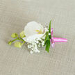 Set against a subtly textured linen cloth in a soft oatmeal shade, this boutonniere feels like a small work of wearable art, carefully composed to bring a whisper of nature to a formal outfit. At its centre, a pristine white Phalaenopsis orchid unfolds in wide, elegant petals, each one smooth and luminous, like silk under gentle afternoon light. Its throat carries just a breath of yellow-orange and a faint blush of pink, a delicate focal point that invites a closer look. Encircling the orchid is a delicate constellation of Gypsophila, or baby's breath, the tiny white flowers gathered into airy clusters that soften the silhouette and lend an almost cloud-like quality to the design. Slim, vibrant green leaves are positioned with intention, their shapes creating fine lines of contrast that frame the orchid and keep the composition visually balanced. Extending to one side, a slender stem bears three rounded, pale green orchid buds, still closed, offering a quiet suggestion of growth and promise, much like a new chapter beginning in one of Oxford's historic colleges or along the banks of the Cherwell. The stems are wrapped with meticulous precision in a bright pink satin ribbon, its lustrous surface catching the light and forming a neat bow with short, tailored ends that feel both playful and sophisticated. The overall impression is one of gentle minimalism and calm romance: a refined buttonhole that would sit comfortably on a groom's lapel, a prom suit, or a guest's jacket at a celebration, carrying with it the fresh, subtle scent and intimate craftsmanship of a bouquet scaled down to a single, perfect accent.
