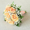 This hand-tied bridal bouquet centers on creamy peach roses, each bloom opening in smooth concentric spirals that glow with a soft, warm light. A mist of white gypsophila-tiny, cloud-like blossoms-wraps the roses and diffuses the bouquet's edges into an ethereal frame, lending a feeling of innocence and quiet wonder. Shiny, deep-green foliage interspersed throughout brings contrast and depth, allowing the peach tones to read as both gentle and vivid against the leaves' cool sheen.

The stems have been lovingly wrapped in matching peach satin, the ribbon lying flat and elegant against the hand, and finished with a neat row of small pearls that catch and reflect light like memories held close. When lifted, the arrangement feels cool and balanced, the fragrance understated-fresh, floral, and slightly green-evoking an early summer stroll by Port Meadow. This bouquet is designed to rest lightly in the bride's hands while making a composed, tender statement.

Prepared with local care by Flowers Oxford, this bouquet suits a ceremony in a chapel off St Giles or a reception in a family garden in Summertown. Its classic lines and restrained palette make it equally fitting for a wedding, anniversary, or as a refined gift to mark a new chapter-an intimate expression of affection crafted with precision and heart in the heart of Oxfordshire.
