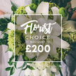Bathed in soft morning light, this Florist Choice Bouquet from Oxford radiates quiet luxury. The dominant whites are large lilies, their petals unfolding with measured grace, complemented by clusters of smaller white blooms to add cloud-like volume. Lime-green blossoms-textured and luminous-provide a bright, contemporary counterpoint, reminiscent of Green Trick dianthus or pale hydrangea accents, while dark green foliage such as eucalyptus and ruscus adds depth and a natural, garden-fresh feel. Hand-tied and held by a person in a light gown, the arrangement sits against a softly blurred background that hints at a wedding or formal occasion. Overlaid at the center is a white frame bearing Florist Choice Bouquet, with the price ?200 clearly displayed at the bottom. From Flowers Oxford, this image suggests a premium gift ready for same-day delivery across Oxford neighborhoods, including Jericho, Oxford City Centre, and Summertown. It embodies a modern classic of contrast and calm, a bouquet designed to convey celebration, love, and refined taste in equal measure.