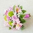 Meticulously crafted by local Oxford florists, this radiant bouquet brings together a harmonious palette of soft pink, refreshing green, and crisp white, all captured on a subtly textured, pale background evocative of Oxford's traditional linen shops. At its center bloom delicate light pink roses, their velvety petals curling inward with a depth of sentiment that reflects many a cherished Oxford romance. Juxtaposed against the softness are apple-green, pom-pom chrysanthemums-each round, fluffy cluster lending playful texture and invoking thoughts of Magdalen College's lush gardens in spring. Light pink and peachy alstroemeria, petals slender and gently speckled, add an airy sophistication, while tiny sprigs of white baby's breath float among the blooms, giving the composition its softly cloudlike character. The arrangement is completed with layers of deep green foliage that frame the bouquet, providing structure and vibrancy. Neatly bound stems peek out from beneath a vivid fuchsia satin ribbon, which coils around the handle in a sleek, modern finish-inviting thoughts of contemporary Oxford style. This image encapsulates the artistry and emotional resonance behind each wedding or anniversary bouquet delivered from the heart of Oxford, making it an ideal gift for celebrations in Marston, Cowley, or beyond. Each flower choice and colour tells a story of joy, love, and community-a signature of Oxford's finest local floristry.
