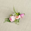 A finely detailed, handcrafted boutonniere lies against a subtle, oatmeal-hued linen background-its palette and textures quietly echoing the understated sophistication found in Oxford's classic architecture. The arrangement's heart is a soft pink rosebud, petals tightly curled yet brimming with the freshness of an early spring on Broad Street. Beside the rose, a gentle, peach-tinged blossom-perhaps Alstroemeria-unfurls its petals to reveal a pale yellow throat with slender, dark lines, adding an exquisite note of natural artistry. Amid these blooms, cloud-like clusters of pure white Baby's Breath and tiny vivid green button mums are tucked in, lending lively movement and a sense of delicate abundance. Slender, deep green blades rise above the florals, while broader dark green leaves, some folded for added interest, provide structure and depth in a way that recalls the careful, layered gardens of Oxford's colleges. The stems are artfully bound with a glossy, fuchsia pink satin ribbon, tied in a perfect, dainty bow that pops brightly against the neutral woven cloth, evoking joy and celebration. Illuminated by soft, natural daylight, the textures of petals, leaves, and ribbon shimmer uniquely, celebrating both nature's bounty and the expert hand of a local Oxford florist. Ideal for weddings held in Oxford's historic venues or celebrations along the river, this boutonniere encapsulates refined beauty, warmth, and a sense of tradition within every elegant detail.
