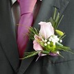 There's a distinct charm in this Oxford-inspired buttonhole, seen as a radiant detail against a classic charcoal suit and eye-catching fuchsia silk tie-perfect attire for a grand college wedding or formal at All Souls. The camera lingers on the boutonniere, expertly crafted for someone with a discerning love of flowers and tradition. Centred around a pale pink rose, the bloom's gentle curves glow in the soft midday light, hinting at tender affection and joyful anticipation. Next to it, a pink alstroemeria offers a glimpse of fine plum veining, its shape and hue echoing the artistry found in the city's flower stalls. Fluffy clusters of white gypsophila add a sense of airy romance, while a compact green chrysanthemum energizes the palette, reminiscent of Oxford's springtime lawns. Fern fronds and long, slender leaves contribute both movement and lush texture, wrapping the flowers in a frame of fresh green. The base is finished with a tidy lavender ribbon bow, neatly securing each bloom and leaf in place. With every detail thoughtfully coordinated, this boutonniere from a skilled Oxford florist radiates happiness and occasion, making it an unforgettable accent for momentous celebrations across Oxford's storied landscapes.