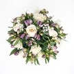 Viewed from directly above against a pure white background, this hand-tied bouquet forms a near-perfect circle of soft ivory and champagne-white roses, deep purple alstroemeria buds, airy baby's breath, and glossy dark greenery. The creamy roses sit at the heart of the design, some fully open to reveal spiral upon spiral of velvety petals, others still gently cupped, as if mid-breath. Around them, tight alstroemeria buds in shades of lavender, plum, and magenta are tipped in fresh green, their elongated forms adding movement and contrast without disturbing the calm elegance of the palette. Sprays of delicate gypsophila thread between the larger flowers, each tiny white bloom like a suspended droplet of light, softening the composition and giving it a weightless, almost cloud-like feel. Broad, rich green leaves frame the bouquet, peeking out between blooms and creating a natural halo that makes the whites and purples glow more intensely against the white backdrop. The lighting is gentle and even, as if it were photographed in soft Oxford daylight, with no harsh shadows, just subtle highlights that make the petals appear freshly cut. The bouquet feels refined yet warmly inviting, the kind of arrangement you might send to a loved one recovering in an Oxford hospital or to accompany a quiet celebration in a Jericho townhouse. It radiates calm sophistication, tenderness, and hope-ideal for moments when you want the flowers to speak in a soft but unmistakably heartfelt voice.