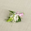 A delicately handcrafted boutonniere is laid carefully on a softly textured, light beige linen-style fabric, the neutral background gently echoing the warm stone of Oxford's historic colleges. At the centre of the piece sits a single white alstroemeria bloom, its broad, slightly ruffled petals opening outwards to reveal fine reddish-brown speckles that pool near the throat, like brushstrokes on porcelain. The flower's stamens are clearly visible, adding a touch of natural intricacy. Nestled just to the left is a tight, conical cluster of vivid lime-green buds, reminiscent of Ornithogalum or a ginger spike, each bud pressed closely to the next and creating a sculptural, almost architectural element against the softness of the alstroemeria. Threaded throughout the design are sprigs of classic white baby's breath, their tiny blossoms forming a misty halo that softens the edges of the arrangement. A base of dark green, sword-shaped leaves supports the blooms, while slimmer, grass-like fronds curve and flick outward, adding lightness and movement, like reeds along the River Cherwell. At the right, the stems are neatly bound with a glossy pink satin ribbon, tied into a small, precise bow that introduces a playful note of colour without overpowering the white and green palette. The lighting is even and natural, revealing every petal vein, leaf edge, and ribbon sheen, and giving the little corsage a fresh-from-the-florist feel. Overall, the image conveys calm, poised celebration, perfect for an Oxford wedding morning, a prom at a local college, or a formal event where a touch of understated elegance is desired on a lapel or wrist.