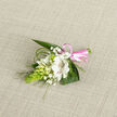 Resting on a pale oatmeal-toned fabric that resembles a favourite linen tablecloth in a North Oxford townhouse, this delicate boutonniere captures the quiet elegance of a thoughtfully planned celebration. The main flower is a white alstroemeria-like bloom, fully open, its silky petals gently flared and traced with fine reddish-maroon stripes inside, adding depth and a subtle sense of character. Encircling it are smaller white buds and partially opened flowers, reminiscent of campanula or lily-of-the-valley, their rounded shapes and creamy tones suggesting new beginnings-a perfect match for a wedding morning near Summertown or a formal dinner in the historic city centre. Wisps of baby's breath weave through the arrangement like a soft, airy veil, their tiny white flowers catching the light and softening the overall look. On one side, a striking bright green cone of clustered buds introduces a modern twist, its sculptural texture contrasting beautifully with the softer petals. Lush, dark green leaves fan out behind, creating a natural frame, while slender, arching strands of fine green foliage curve gracefully around the corsage, echoing the gentle lines of riverside grasses along the Thames. At the base, a neat, glossy pink satin ribbon is wrapped tightly around the stems and tied into a small bow, adding a hint of playful colour and marking the piece as festive yet refined. The image conveys careful craftsmanship and fresh, cool beauty-a floral accessory ready to be worn on a lapel, dress, or wrist for a milestone event filled with emotion and memory.