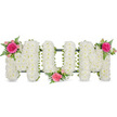 A lovingly crafted floral memorial spelling MUM is shown in crisp detail against a stark white background, creating the impression that the letters are floating in calm, empty space. Each of the three capital letters is built on a discreet dark green framework, but the structure almost disappears beneath a dense covering of white spray chrysanthemums. These tiny blooms sit shoulder to shoulder, forming a thick, padded surface that seems both soft and steady, like a gentle resting place. Their petals catch the light with a subtle sheen, giving the whole tribute a serene, luminous quality reminiscent of soft daylight falling over Oxford's historic stone buildings. Along the base, a slim band of rich green ribbon adds definition and echoes the natural tones in the accent flowers. To break the expanse of white and introduce emotion, three identical clusters of pink flowers decorate the tribute: one at the upper left corner of the first M, one cupped into the lower curve of the U, and one at the upper right of the last M. Each cluster features a striking fuchsia rose surrounded by softer pink spray roses and buds, with airy ferns spilling gently over the chrysanthemum base. The combination of bright pink, fresh green, and clean white creates a balanced, heartfelt composition that speaks of admiration and gratitude. It is easy to imagine this MUM tribute resting beside a coffin at a funeral in Oxford or being carried to a graveside after the service, a final floral message of love from children and family who want to honour a beloved mother's memory.