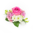 A compact, hand-arranged corsage sits against a pristine white background: at its center a plush bubblegum to fuchsia pink rose, its tight inner petals gradually unfurling into a velvety dome that draws the eye. Around the rose a halo of soft pastel pink and lavender hydrangea florets creates a cloud of airy volume, each tiny petal catching the light and lending a romantic, garden-fresh softness. Nestled beneath and slightly to one side, two creamy white, trumpet-shaped blossoms-reminiscent of small alstroemeria or miniature lilies-tilt their greenish throats upward, their satiny petals offering a bright, pure contrast to the deeper pink. Broad, glossy deep-green leaves form a grounding base, their smooth surfaces and rounded shapes visible at the composition's edges. Slender green buds with the faintest hint of yellow push upward from the sides, introducing a sense of growth and promise, while a small cluster of luminous white pearls cascades gently at the lower right, varying in size and adding a refined, heirloom-like shimmer. The whole arrangement is bathed in soft, natural light that renders petal texture, subtle hue shifts, and the cool freshness one expects from flowers picked within hours of styling. This is a piece that reads as both intimate and formal, perfect as a bridal corsage, prom accent, or anniversary keepsake for celebrations across Oxford-from a Botanic Garden wedding to a university graduation on the High Street. A florist's touch is evident in the balanced proportions, scent of fresh-cut blooms, and the quiet elegance that suits spring and summer occasions in the city.