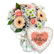 Captured against a bright, seamless white backdrop, this Mother's Day gift arrangement feels both modern and warmly personal, as if it has just been set down in a sunlit Oxford living room near Headington. At the centre stands a clear glass vase with subtly rounded sides, its neck encircled by a modest tie of rustic twine that adds a hint of countryside charm to the clean design. The vase brims with a mixed bouquet of fresh-cut flowers in gentle pastel shades: peach-pink roses open in smooth, layered spirals, their petals soft and velvety, while several peach gerbera daisies stretch their wide, daisy-like faces outward, each one anchored by a deep brown or black centre that draws the eye. Between them, fine sprays of white baby's breath weave through the arrangement like delicate lace, creating a light, airy feel. Smaller white and pale green chrysanthemums provide texture and fullness, nestling among glossy green foliage that adds depth and a freshly picked look, reminiscent of flowers gathered from gardens along the Oxford Canal. To the right of the bouquet, a heart-shaped Mylar balloon leans into the frame. Its surface is a crisp white or cream, patterned with tiny golden-peach dots that give the impression of scattered confetti. At the balloon's centre, a peach-toned heart encloses the message Happy Mother's Day in a stylish coral-peach script, the flowing letters suggesting care and affection. The overall composition-flowers, balloon, and invisible but implied card-captures the essence of a thoughtful Mother's Day surprise, perfect for celebrating mums across Oxford with a mix of tenderness and quiet celebration.