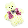 A floral teddy bear tribute stands out crisply against a pure white background, as if it has been gently set down for one quiet, thoughtful moment. The bear's full shape-circular head, alert little ears, rounded body, and splayed paws-is entirely constructed from compact white chrysanthemums, each bloom pressed closely to the next to create a dense, velvety coat. Their petals appear soft and feathery, giving the impression of a cuddly toy translated into flowers. Subtle cream tones at the centres of some blossoms stop the white from feeling stark, adding warmth and a natural softness. The face is defined with care: two small, dark eye accents and a neat triangular black nose form a simple, endearing expression, while the suggestion of a faint smile rests just above the muzzle, hinting at comfort and kindness. Over the teddy's chest, a decorative floral waistcoat is created using deeper shades of pink and mauve flowers, laid in two mirrored panels that echo the line of a tailored vest. In the gap between them, at the neckline, sits a small bow made from sheer purple netting, its airy loops catching the light and introducing a gentle sense of movement. No background props or greenery distract from the design; everything is calm, clean, and focused on the teddy itself. This arrangement feels especially fitting for a child's funeral, a memorial in one of Oxford's peaceful churches, or a poignant farewell near the dreaming spires, where families seek a tribute that speaks of innocence, love, and the soft echo of cherished memories.